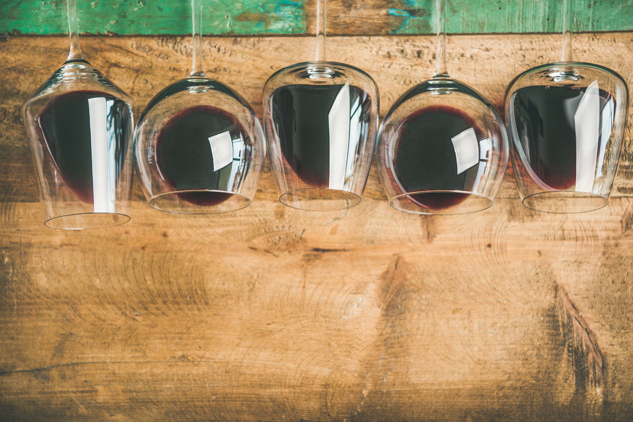 5 glasses with red wine lying down on a wooden table