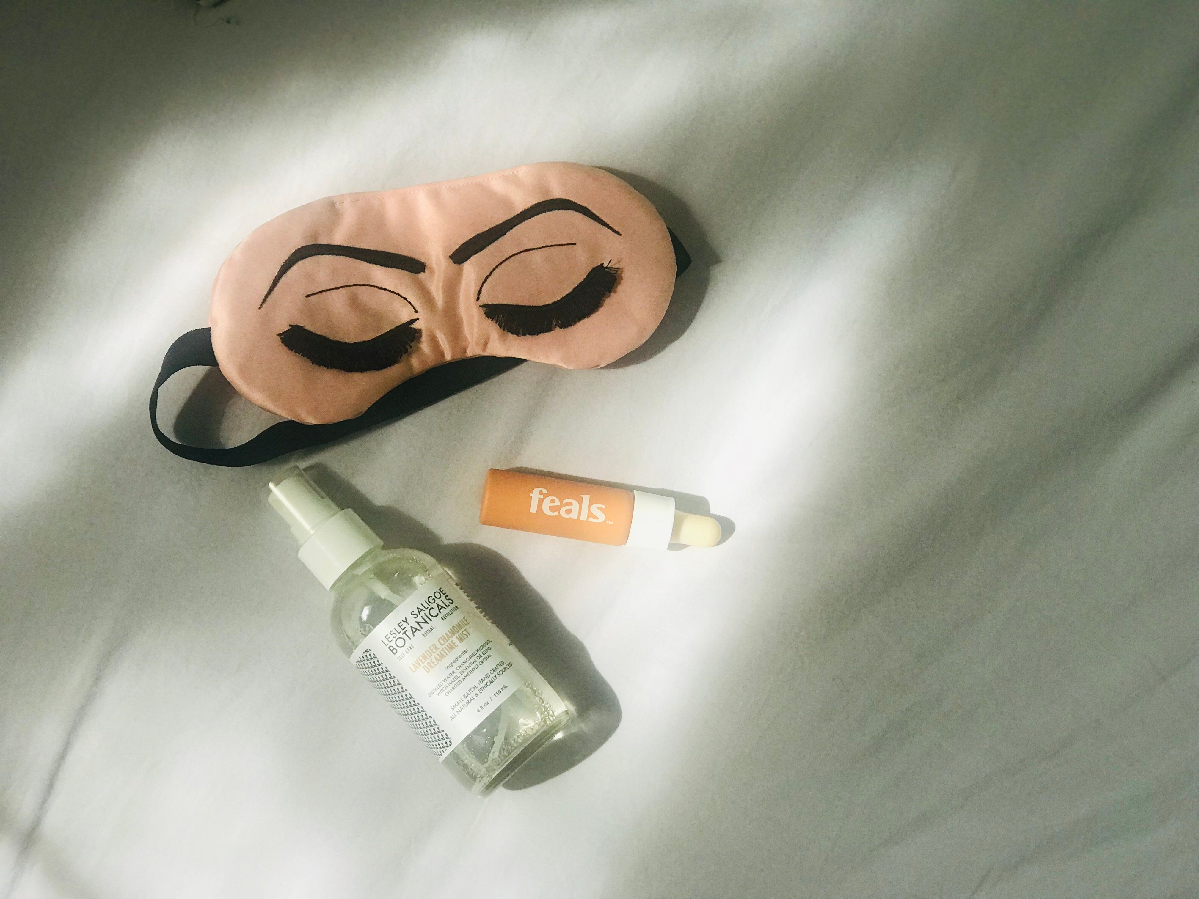 feals on a bed with and eye mask and skin care
