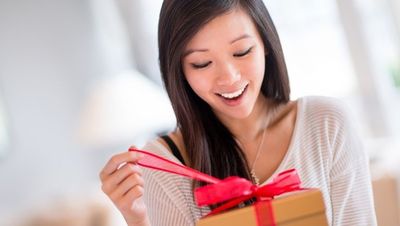 woman in white shirt opening gift with smile