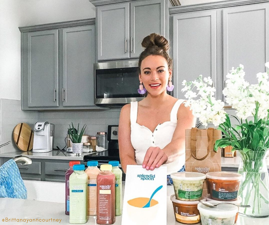 Woman stands in light colored, bright kitchen with a colorful range of splendid spoon soups and smoothies