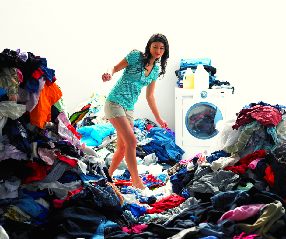 women surrond my piles of washing with washing machine in the background